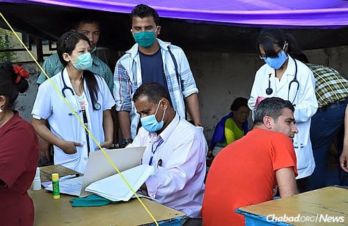 Aid and medical workers in a tent outside Chabad of Kathmandu treat the injured and ill following a 2015 earthquake.