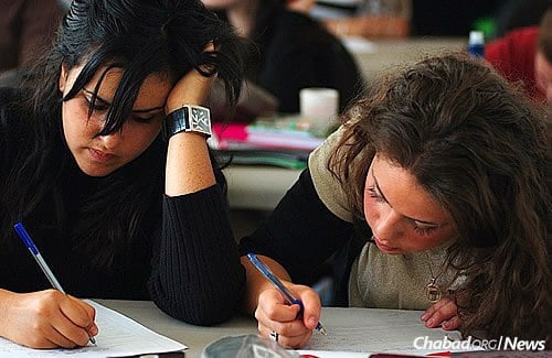 Two seminary girls are absorbed in taking notes while learning the mitzvah of mikvah. (Photo: mushkaphotography.com)