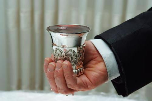 Holding the ceremonial cup of wine for Kiddush or Havdalah.
