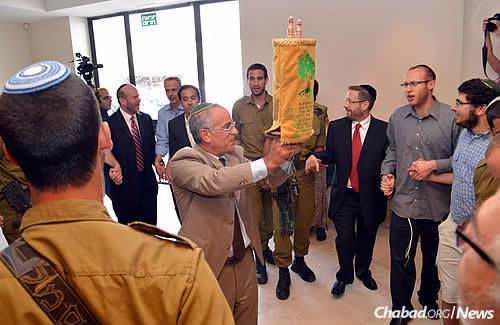 Stuart Steinberg displays the new Torah to the crowd. Its smaller size makes it easier for IDF troops to carry it with them. (Photo: Lone Soldier Center)
