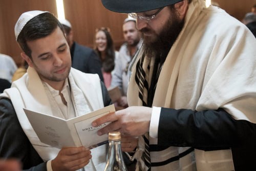 A mohel assisting a father to read the text. Photo: Clifford Lester