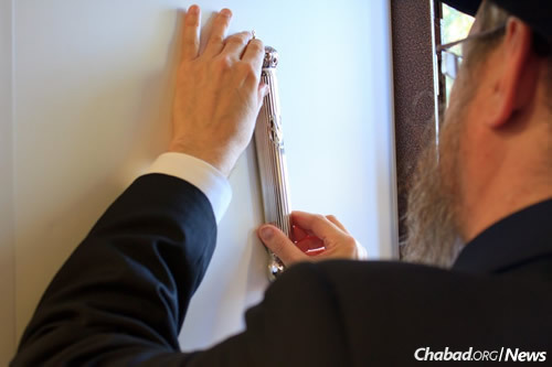 Rabbi Berel Lazar affixes the mezuzah. (Photo: Chabad of the CIS)
