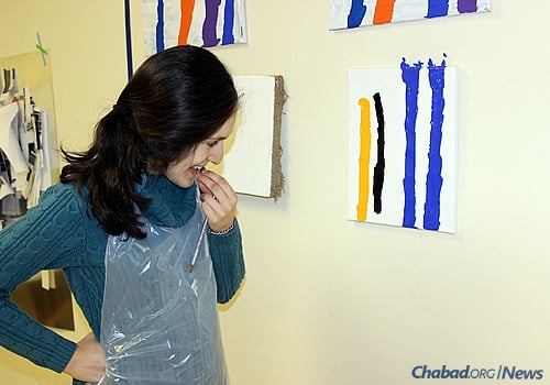 Aislinn Wendrow, 22, examines some of her paintings at Soul Center Mini, the precursor to a new Friendship Circle of Michigan program where young adults with special needs can share their creative skills with the community.