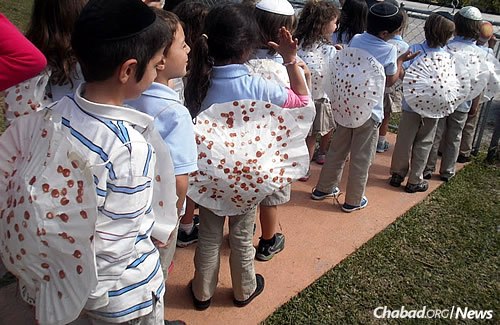 The younger set is on their way to a model seder, complete with homemade “matzah” on their backs.