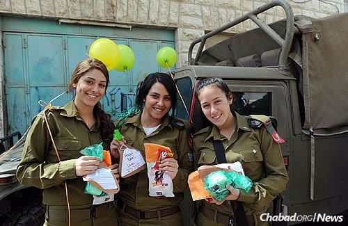 Soldiers hold snacks and letters from supporters in Israel and abroad, especially from children.
