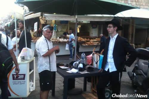 Yeshivah students wrapped tefillin with shoppers at the Machane Yehuda outdoor market in Jerusalem.
