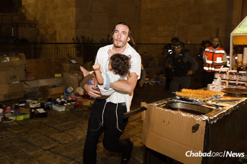 A man carries a baby injured in a knifing attack in the Old City of Jerusalem. A Jewish family and a second man were stabbed while walking near the Lion&#39;s Gate. (Photo: Yonatan Sindel/Flash90)