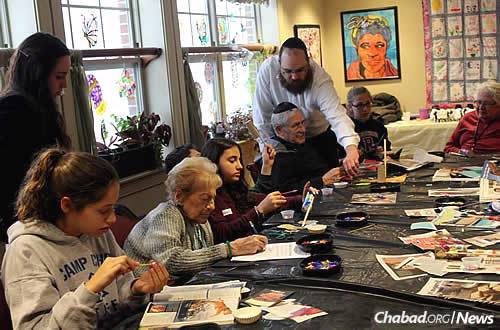 “Linking Hearts,” a project of Valley Chabad in Woodcliff Lake, N.J., joins middle-school students with seniors in an effort to bridge the Jewish generations by making crafts and engaging in conversation. Rabbi Yosef Orenstein, co-director of the Teen Leadership Initiative at Valley Chabad helps one of the residents. Seated at far left is Ellie Grabow.