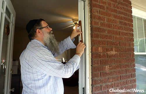 Rabbi Yonason Biggs, associate director of Chabad of Great Neck, N.Y., and Shoshi Litvin&#39;s father, hangs the first mezuzah at the recent opening event.