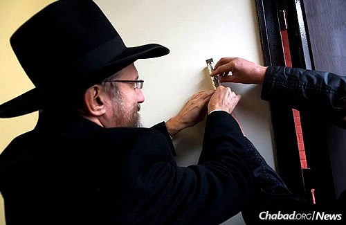 Chief Rabbi of Russia Berel Lazar hangs a mezuzah at the entrance to the main building.