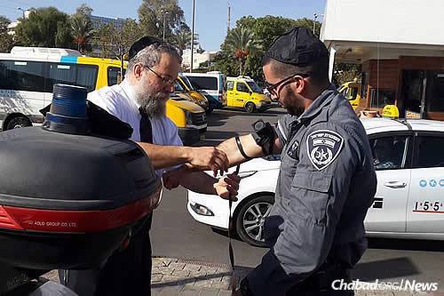 Raichik helps a border policeman in Be’er Sheva don tefillin.