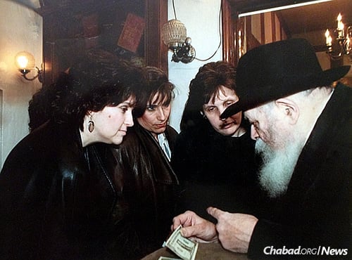 The editorial committee of the cookbook, from left, Cherna Light, Cyrel Deitsch and Esther Blau, receive dollars and a blessing from the Lubavitcher Rebbe—Rabbi Menachem M. Schneerson, of righteous memory—for their work.