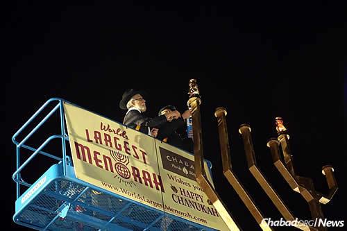 At the top of the gold-colored menorah for the annual Chanukah lighting. Adams lights the shamash, the utility candle used ti ignite the other ones. (Photo: JDN)