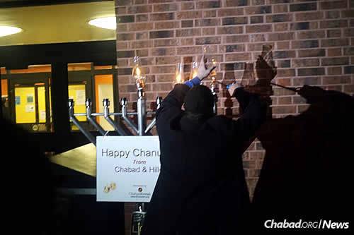 The rabbi lights the Chanukah candles on the third night of the eight-day holiday.