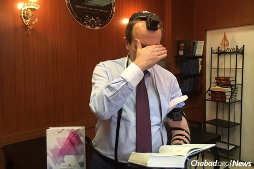 Gov. Alexander Levinthal of Birobidzan wraps tefillin for the first time.