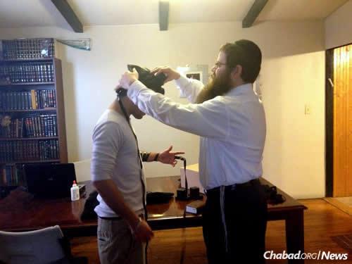 The rabbi wraps tefillin with a student.