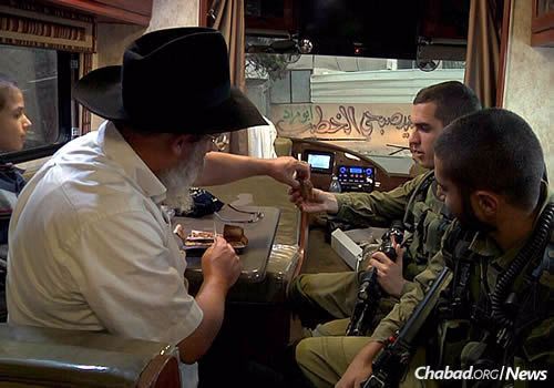 Rabbi Yosef (“Yossi”) Nachshon of Chabad of Kiryat Arba hands out slices of “lekach” (honey cake) to Israel Defense Forces soldiers for Rosh Hashanah, signifying a sweet New Year.