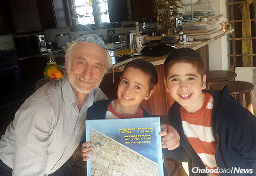 From left: A Jewish community member in Rhode Island receives a box of shmurah matzah from young Chabad emissaries Levi and Mendel Laufer.