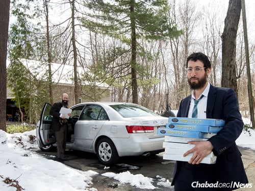 Rabbi Lavy Kosofsky, a Chabad-Lubavitch emissary in Longmeadow, holds boxes of shmurah matzah in Hatfield, Mass. His father, Rabbi Noach Kosofsky, principal of the Lubavitcher Yeshiva Academy in Longmeadow, stands by the car. (Photo: Pearl Gabel)