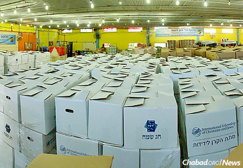 Boxes upon boxes of kosher-for-Passover goods in a warehouse in Lod, Israel, will be distributed to Jewish individuals and families in need this Passover, sponsored by the International Fellowship of Christians and Jews. Inked on the side of the white cartons in Hebrew are the words: “Happy Holiday!”