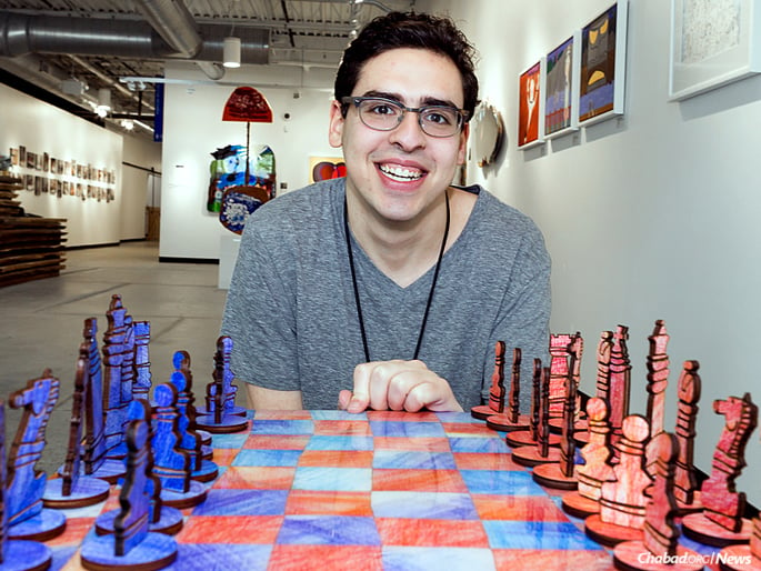 Artist David Kole sits in the Soul Center’s Rissman Gallery in front of the chess set he designed and made. (Photo: Brandon Schwartz)