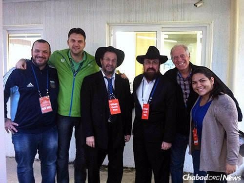 Chabad-Lubavitch of Rio de Janeiro will play an active role in welcoming and caring for the 40,000 Jewish visitors expected to descend on the city this summer. Rabbi Yehoshua Goldman (fourth from right) and Rabbi Eliyahu Haber (to his right) will serve as Jewish chaplains for the Games. Here, they pose with staff at the Olympic Village, including head of security Tsur Bunim (second from right).