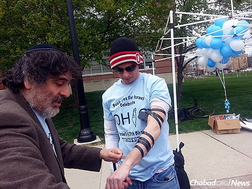 The rabbi wraps tefillin with David Katz.