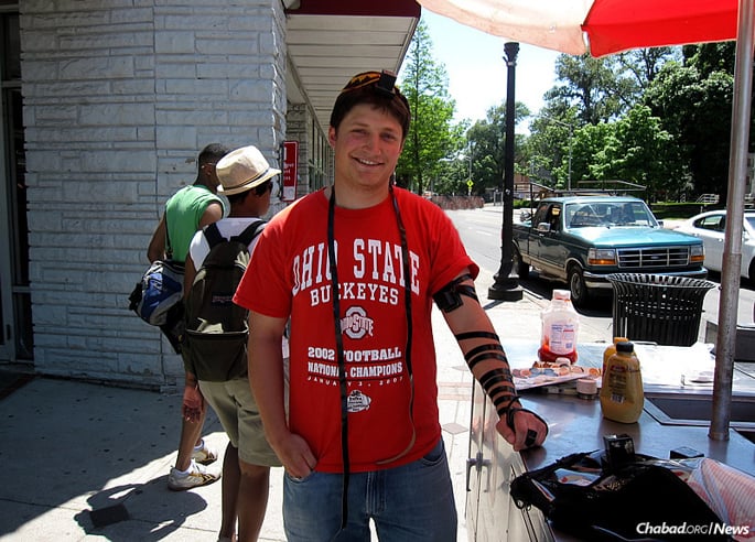 Dan Heldman dons tefillin near the well-known and long-established kosher hot-dog cart at Ohio State University in Columbus, initiated by Rabbi Zalman and Sarah Deitsch of the Schottenstein Chabad House at OSU, soon after the couple arrived on campus.