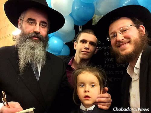 Rabbi Avraham Wolff, left, chief rabbi and director of the Jewish Community of Odessa and Southern Ukraine, holds an “upshernin” (a hair-cutting ceremony for 3-year-old boys). At right is Rabbi Shmulik Greenberg, director of development for the orphanage.
