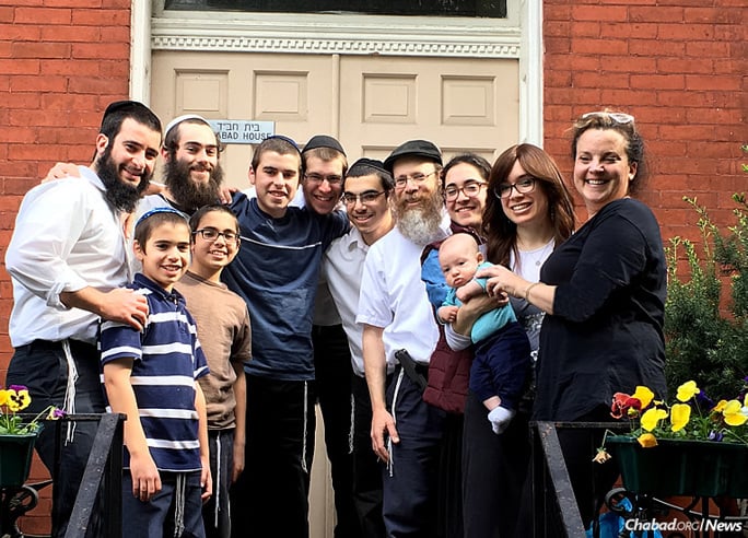 At Chabad on Campus in Pittsburgh, everyone is family. From left: Rabbi Shmuli and Chasi Rothstein, and Rabbi Shmuel Weinstein and family, with University of Pittsburgh graduate Yaakov Newman, second from left at top, who is now studying at the Mayanot Institute of Jewish Studies in Jerusalem, and his mother, Nancy Newman, far right.