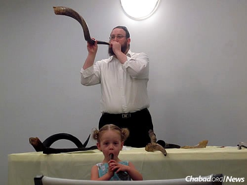 Checking out shofars prior to Rosh Hashanah at a Shofar Factory Workshop. The rabbi gets a little help from a little participant.