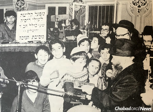 Rabbi Henich Rapoport, right, pictured here with immigrant children in Israel, hosted famed 19 Kislev farbrengens at his home in Moscow during dangerous times.