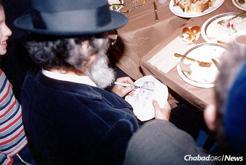 Yaacov Agam, center, works on a sketch of Rabbi Binyamin Klein at the bris of the latter’s son. (Photo: Jewish Educational Media/The Living Archive)