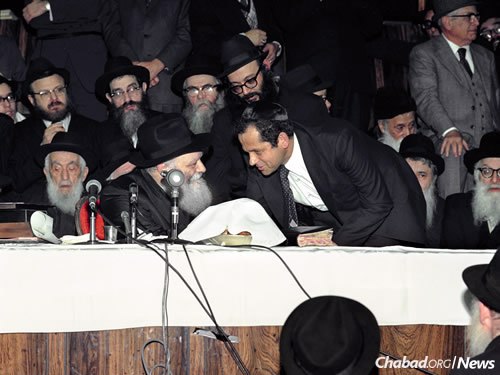 Yosef Ciechanover with the Rebbe at a farbrengen. (Photo: Jewish Educational Media/The Living Archive)